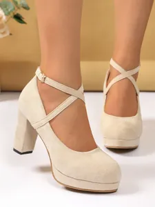 Primo piano di scarpe beige scamosciate con plateau, cinturino a incrocio e tacco largo