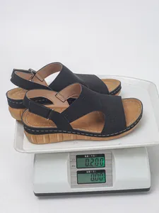 Detailansicht leichter schwarzer Keilsandalen mit Lochmuster auf einer Waage