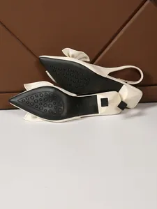 Close-up detail showing the anti-slip black sole of cream slingback heels with bow