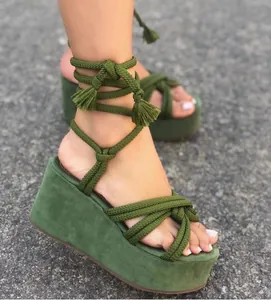 Close-up macro shot of green platform wedge sandals with lace-up rope ankle straps