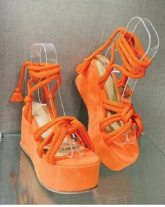 Detailed view of vibrant orange lace-up wedge sandals with thick platform soles.