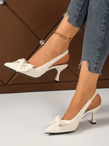 Elegant white slingback high heels with bow detail and textured finish on feet.