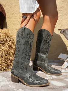 Close-up of grey embroidered Western high boots with pointed toe and chunky heel.