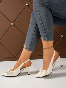 Detailed side view of elegant white pointed-toe slingback sandals featuring a chic bow