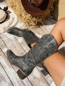 Close-up of grey embroidered tall western boots with intricate patterns and chunky heel