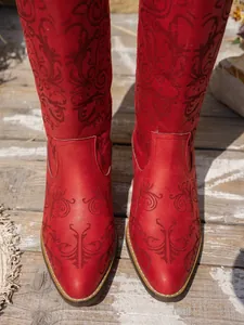 Close-up detail view of red embroidered western boots with pointed toe and chunky heel style