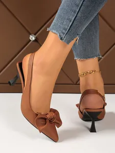 Detailed shot of brown pointed-toe slingback heels featuring a stylish front bow knot