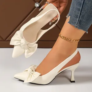 Elegant white pointed-toe slingback heels featuring an oversized bow and kitten heel.