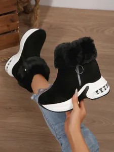 Close-up of black platform snow boots with faux fur trim and side zipper detail