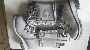 Detailed view of grey mid-calf knight boots with knit cuffs and metallic buckle straps