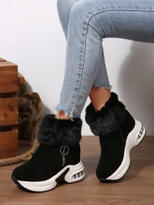 Lifestyle view of women's black platform winter boots with faux fur collar and side zipper.