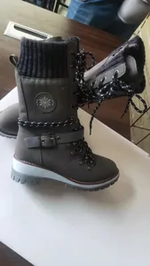 Close-up of grey winter boots with knitted wool cuff, belt buckle, and snowflake detail.