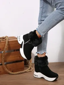 Black faux fur-lined platform snow boots for women with side zipper and rustic backdrop