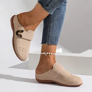Detailed side view of beige women's closed-toe mules with perforated floral patterns and buckle.