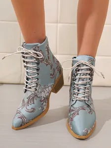 Detailansicht eleganter hellblauer Satin-Stiefeletten mit Stickerei und Blockabsatz.