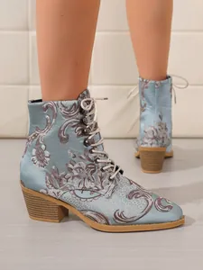 Nahaufnahme der blauen, bestickten Satin-Stiefeletten mit Schnürung und Blockabsatz.