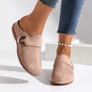 Close-up of women's beige closed toe clogs with laser-cut patterns and gold buckle.