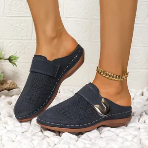 Detail of navy blue closed-toe mules with perforated patterns and metal buckle