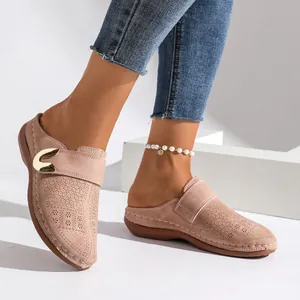 Detail view of pinkish nude perforated closed-toe mules featuring gold metal buckle
