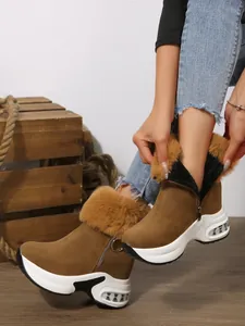 Close-up detail of women's brown platform snow boots featuring faux fur trim and side zipper