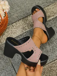 Detail view of pink suede-like sandals with metal rivets and black platform heels