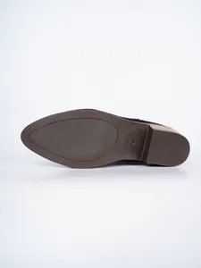 Detailed view of the textured non-slip rubber sole on a black suede pointed-toe boot