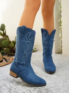 Detailed shot of blue suede western boots featuring intricate white flame embroidery