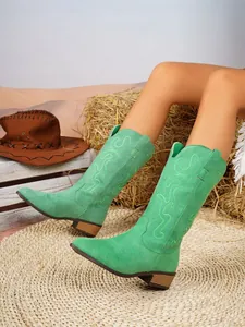 Detail view of green suede pointed-toe cowboy boots featuring elegant floral embroidery