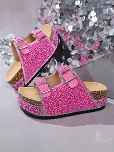Detailed view of pink platform slides featuring pearl and rhinestone double buckle straps