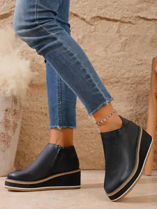 Detailansicht der schwarzen Retro-Keilstiefeletten mit Plateausohle und Reißverschluss
