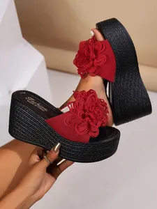 Detailed view of red wedge platform sandals with a large flower and braided sole