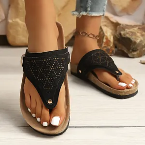 Detailed macro view of black retro flat thong sandals for women on a wooden floor.