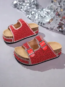 Detail view of red platform sandals with sparkling pearls, rhinestones, and metal buckles.