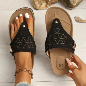 Close-up of black vintage flat flip-flops with decorative cutouts and gold accents