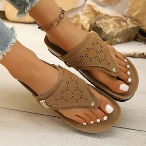 Close-up of women's vintage brown flip-flops with laser-cut patterns worn on feet.