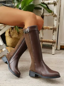 Close-up of brown suede and leather knee-high boots with side zipper and buckle