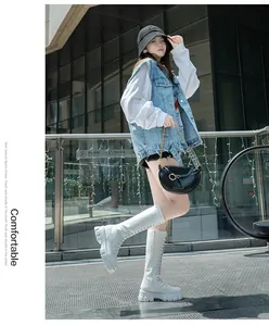 A detailed view of women's white chunky knee-high boots with side zipper on model.