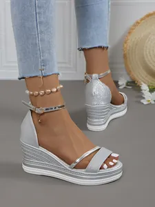 Nahaufnahme der silbernen Glitzer-Keilsandaletten mit Plateausohle und Ankle-Strap-Verschluss