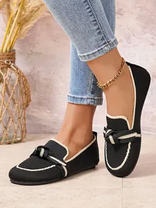 Detail van zwarte fly-knit loafers met crèmekleurige bies en knoop voor dames