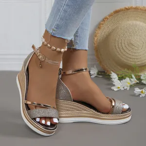 Detalle de sandalias con cuña de purpurina con tiras de oro rosa y suela de paja