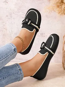 Elegante zwarte fly-knit loafers met crème knoopaccent gedragen door een model