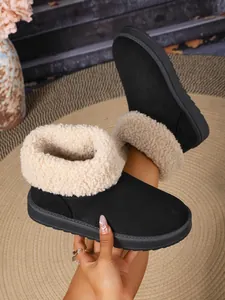 Close-up van warme zwarte sneeuwlaarzen met pluizige beige imitatiebont voor de winter