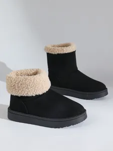 Detailopname van zwarte suède sneeuwlaarzen met een zachte beige rand van imitatiebont.