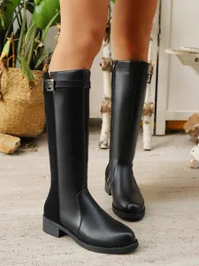 Close-up detail view of black knee-high knight boots featuring a buckle strap and side zipper.