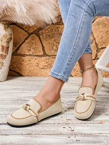 Close-up van beige gebreide loafers met gedraaide knoop gedragen met een blauwe jeans.