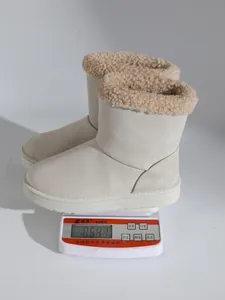 Detail van lichte beige sneeuwlaarzen met kraag van imitatiebont op een weegschaal.
