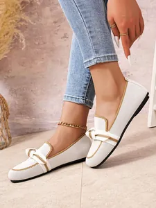 Detailweergave van ademende witte fly-knit loafers met gouden knoop