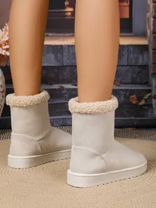 Detailweergave van beige winterlaarzen met zachte rand van imitatiebont op een tapijt