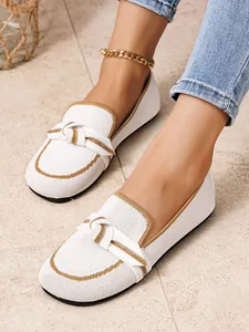 Gedetailleerd overzicht van witte fly-knit loafers met knoopdetail en bruine afwerking