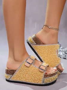 Detailed view of golden pearl and rhinestone double buckle cork platform slippers.